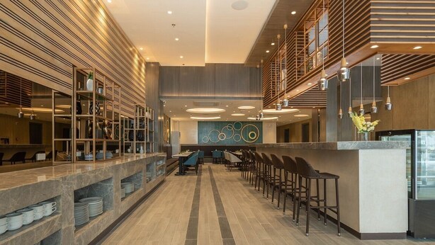 A modern restaurant with a long counter, multiple seating areas, and a decorative wall with circular patterns. - Bayfront Hotel Cebu - Capitol Site (Cebu City)