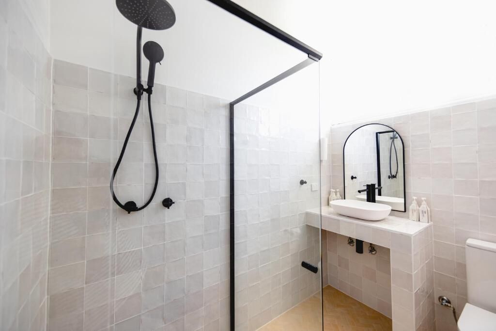 A modern bathroom with a glass shower enclosure, a white sink with a mirror, and a toilet.