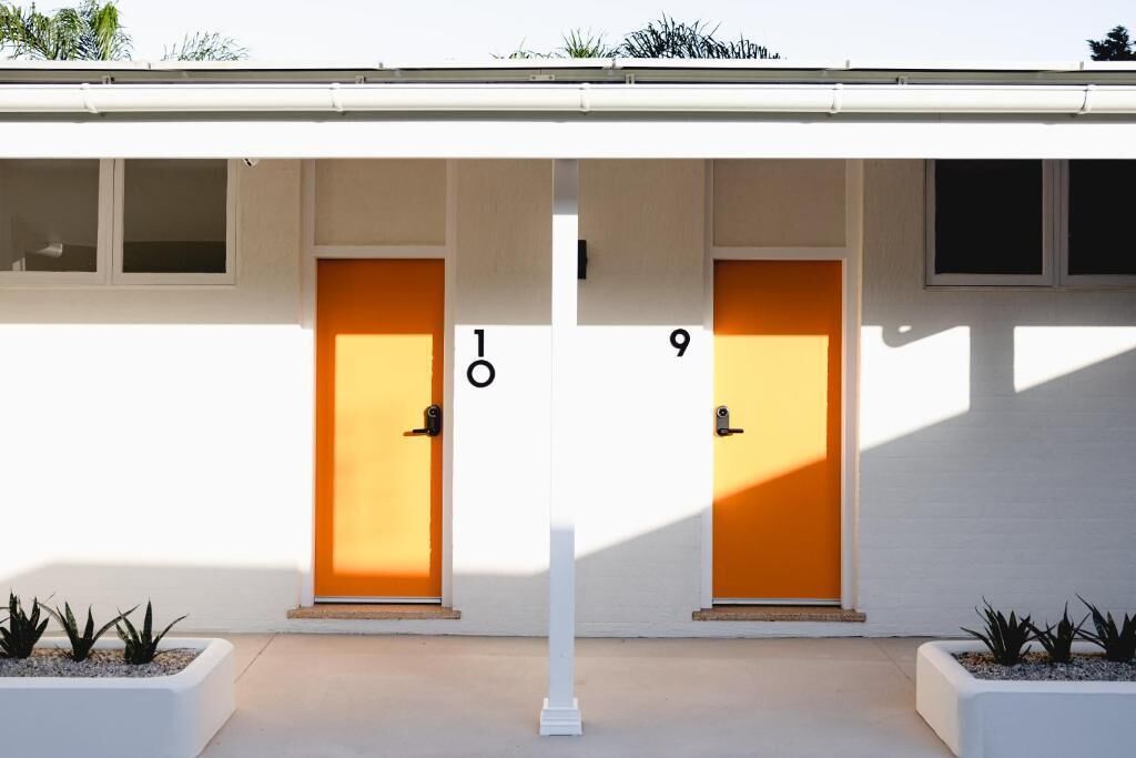 A building with two doors labeled 10 and 9, white exterior walls, and small planters with plants at the entrance.