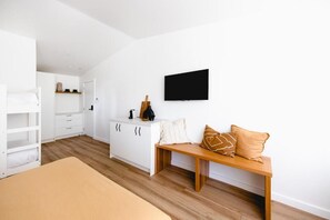A bedroom with a bunk bed, a wooden bench with pillows, a white dresser, and a flat-screen TV mounted on the wall. - THE BERRY VIEW (Berry)