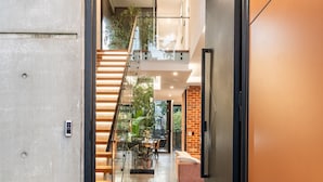 A modern interior with a staircase leading to an upper level, a seating area, and a glass door entrance.