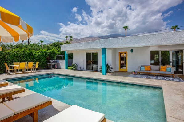 A modern house with a swimming pool, outdoor furniture, and a patio area.