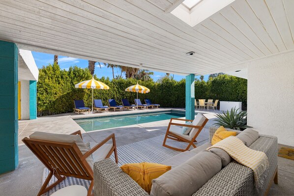 Relax by the serene pool surrounded by lush greenery and comfortable seating options.