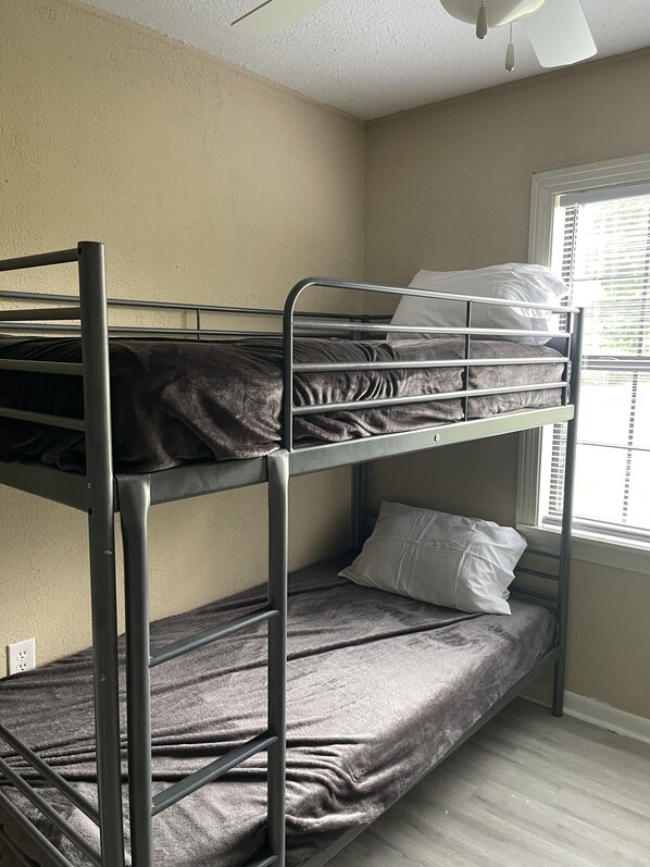 Dormitorio con literas, ventana y ventilador de techo.