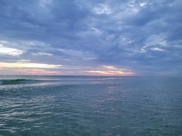 Enjoy a serene beach experience with gentle waves and a clear horizon.