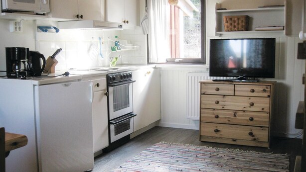 A compact kitchen with white cabinets, a stove, a microwave, and a television on a wooden cabinet. - Nice Home in Transtrand With Sauna and Wifi (Transtrand)