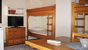 A room with bunk beds, a wooden dresser, a television, and a table with a remote control. - Nice Home in Transtrand With Sauna and Wifi (Transtrand)