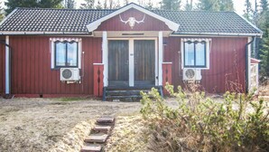 A red building with a front door, two windows, and a decorative bull skull emblem. - Nice Home in Transtrand With Sauna and Wifi (Transtrand)