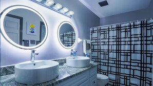 Un baño con dos lavamanos, un espejo y una cortina de ducha.