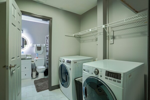 A laundry room with two washing machines, a toilet, and a mirror.