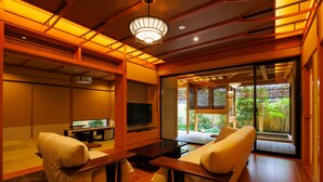A traditional Japanese-style living room with tatami flooring, a low wooden table, and a television. - yado-shiontei (Yonago)