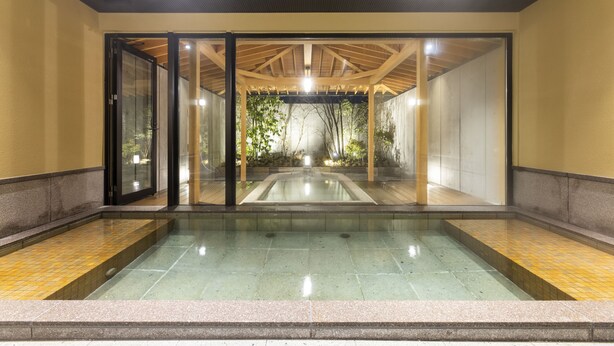 A modern indoor pool area with glass doors, a wooden ceiling, and a tiled floor. - yado-shiontei (Yonago)