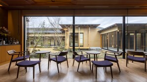 A modern interior with large windows, wooden flooring, and a seating area with chairs and tables. - yado-shiontei (Yonago)