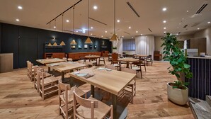 A modern restaurant with wooden tables and chairs, pendant lighting, and a potted plant. - HOTEL LEPO CHAHAL (Matsuyama)