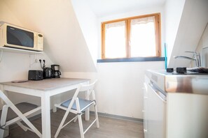 Une petite cuisine équipée d’un four à micro-ondes, d’une machine à café et d’une fenêtre avec des rideaux.