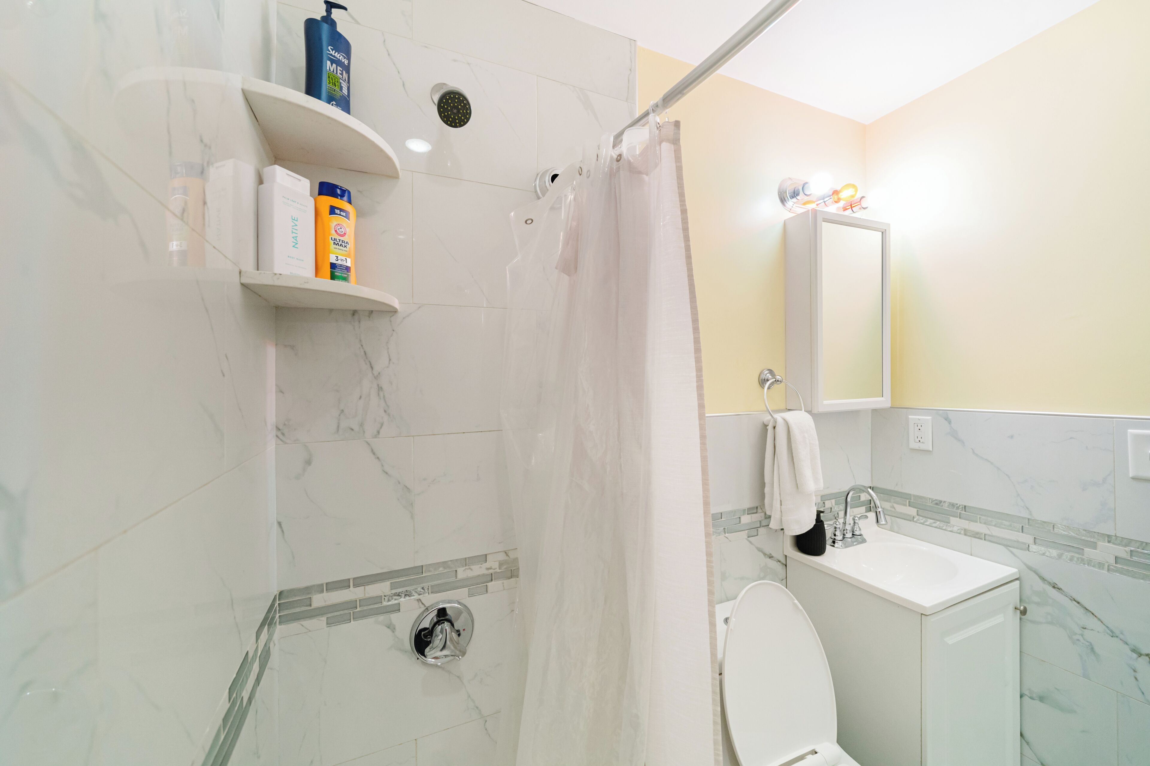Un bagno con doccia, WC, lavandino e pareti in marmo.