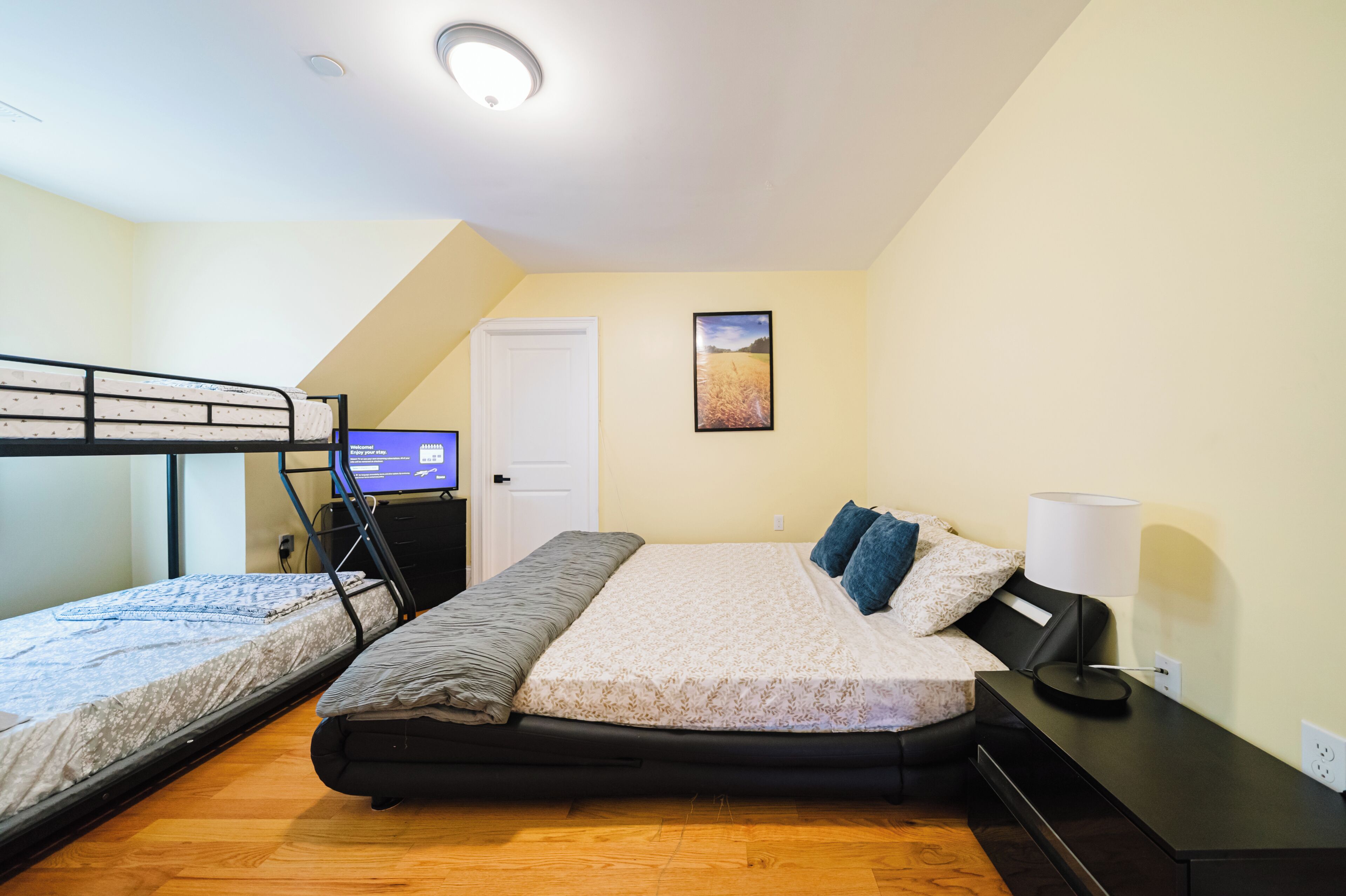 A room with two bunk beds, a desk with a computer, a lamp, and a picture on the wall.