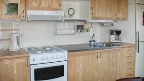 Een keuken met houten kastjes, een witte kookplaat, een spoelbak en een koffiezetapparaat.
