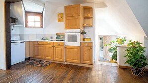 A kitchen with wooden cabinets, a microwave, and a sink. - Gîtes Rocher des Celtes (Dieffenthal)