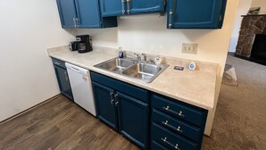 A kitchen with blue cabinets, a dishwasher, a coffee maker, and a sink.