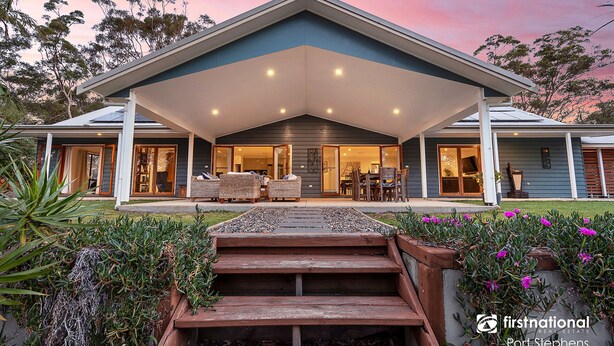 A modern house with a covered patio, a dining area, and a large window overlooking the garden. - Deja Blue Anna Bay (Anna Bay)