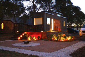 Ein modernes Haus mit Holzfassade, einer sichtbaren Treppe und einer Auffahrt mit Kies und Pflanzen.