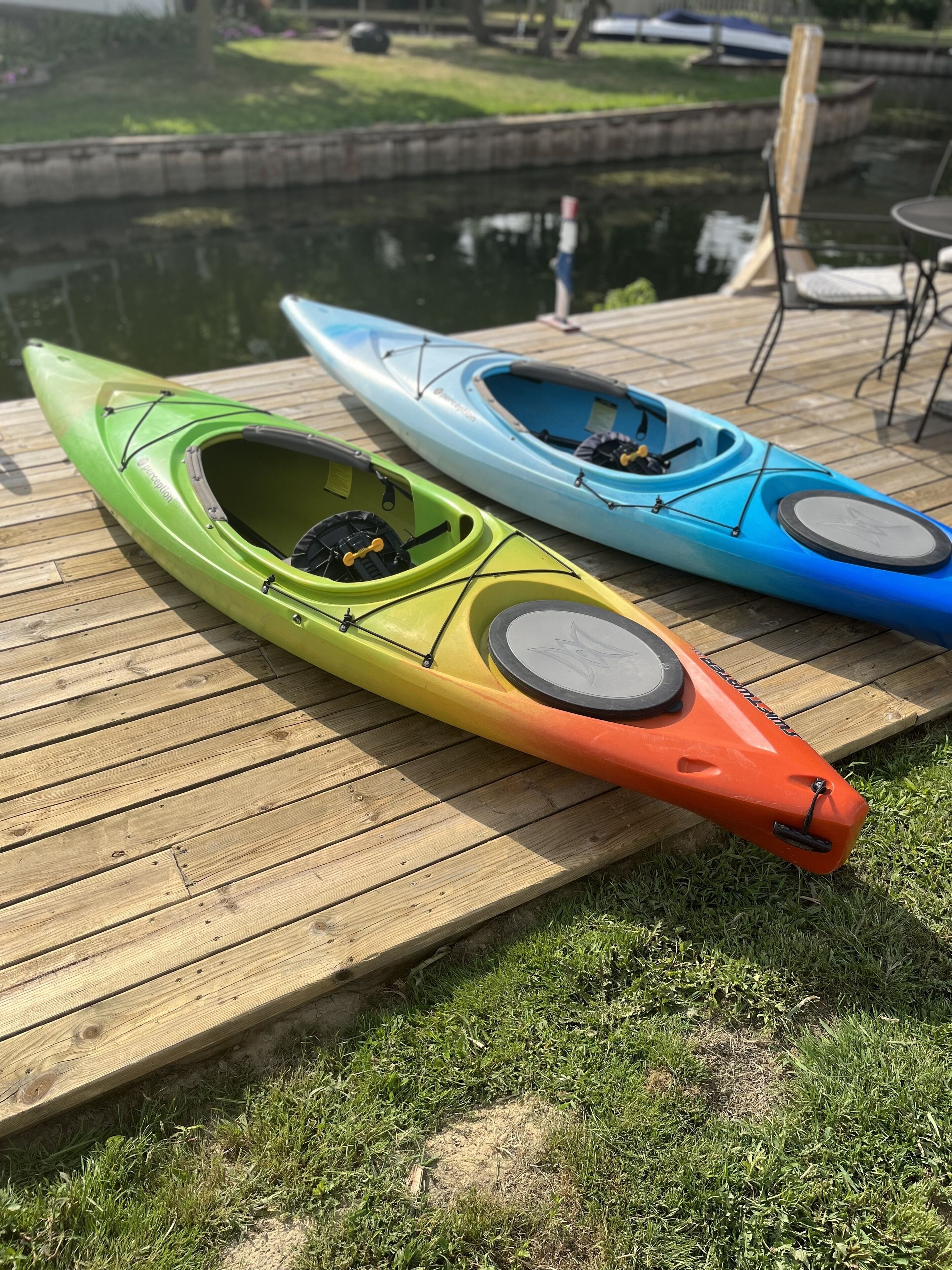 Two kayaks on a wooden dock by a calm body of water.