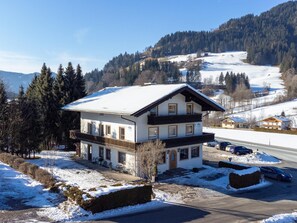 Una villa a due piani con un balcone, un'area di parcheggio e vista su un paesaggio innevato.