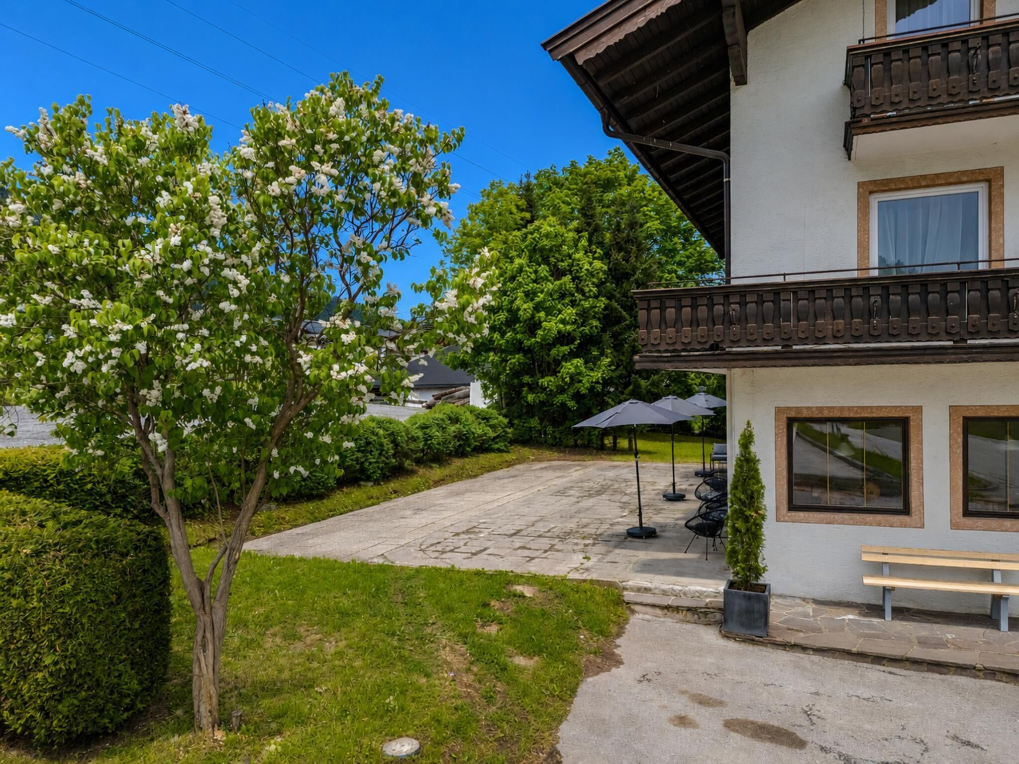 Ein Gebäude mit Balkon, Außenbereich und einem Baum mit weißen Blüten.