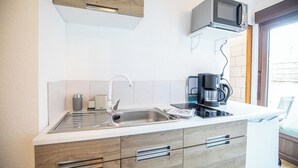 Et moderne køkken med indbygget mikroovn, kaffemaskine og stålvask.
