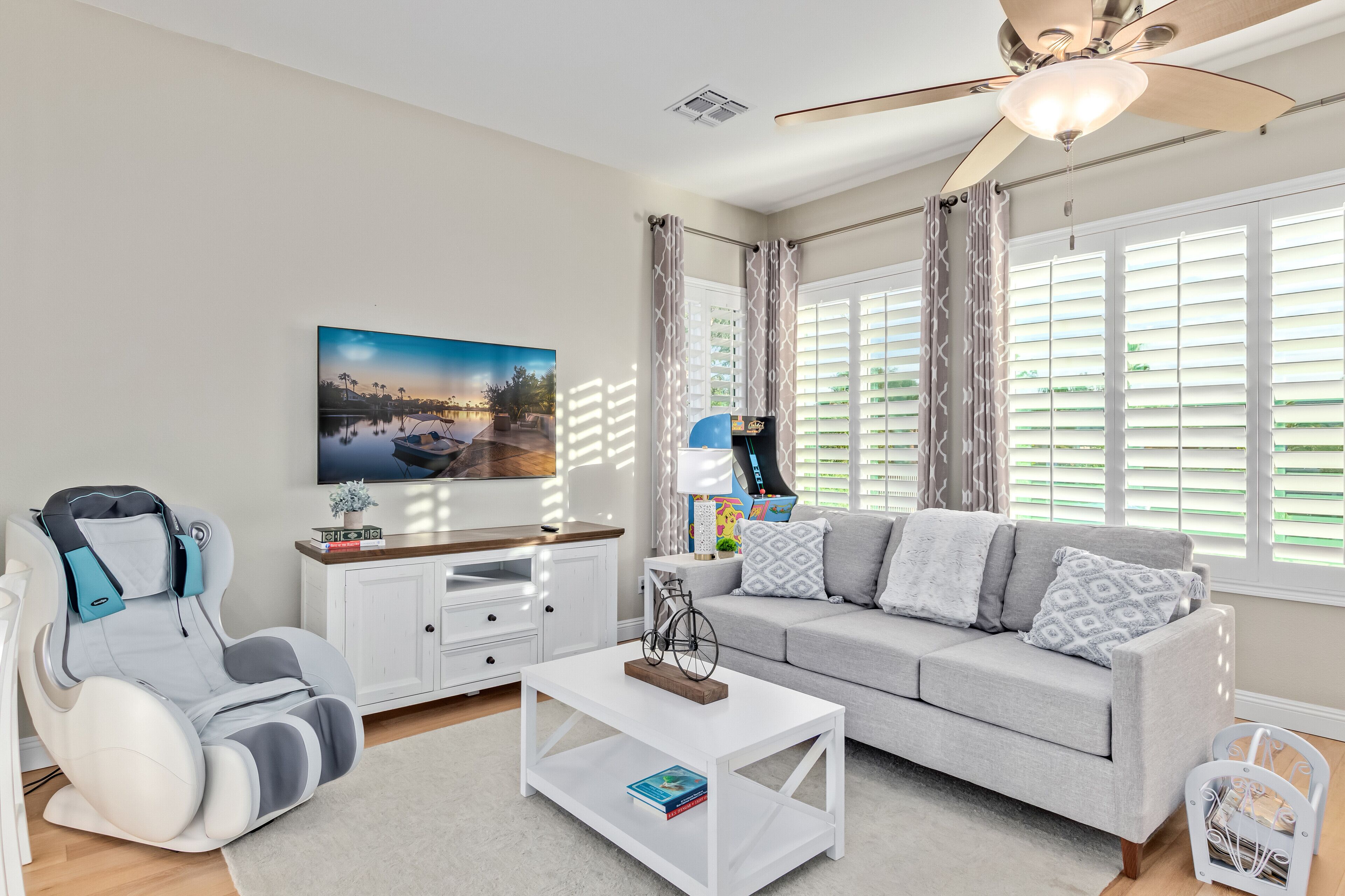 A living room with a sofa, coffee table, massage chair, and a painting on the wall.