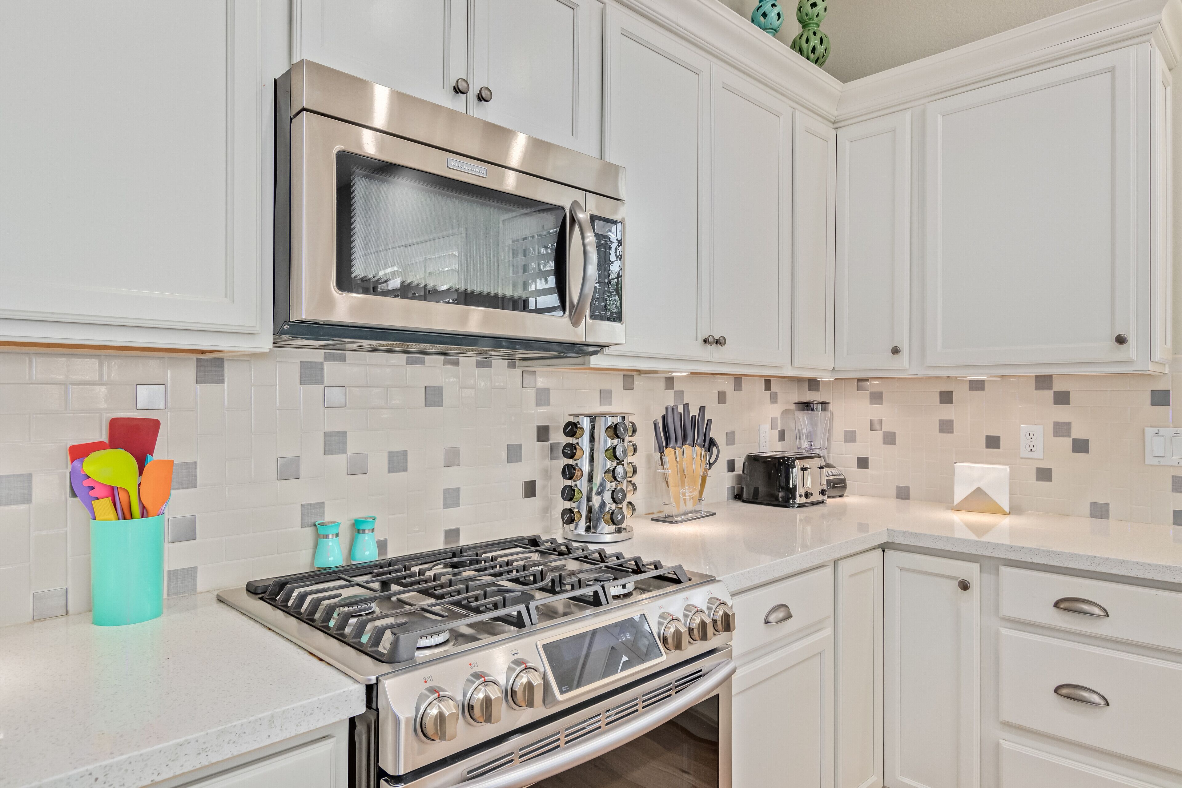 A modern kitchen with white cabinets, a stainless steel stove, and a microwave above it.