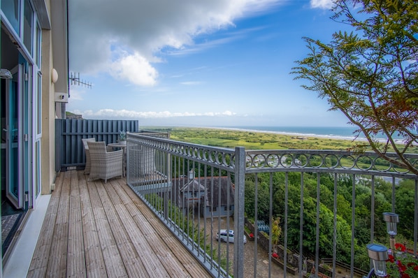 A balcony with a view of the ocean and greenery.