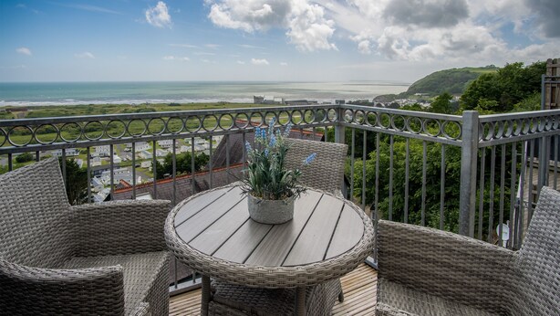 A balcony with wicker furniture and a view of the ocean. - Nautilus - 2 Bedroom Apartment - Pendine (Carmarthen)