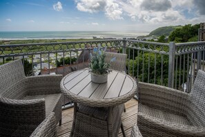 Een balkon met rieten meubilair en uitzicht op de oceaan.