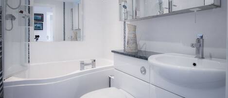 A modern bathroom with a white bathtub, a sink, and a toilet.