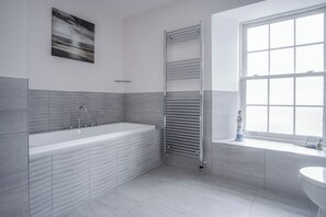 Een aparte badkuip en douche, een haardroger, handdoeken