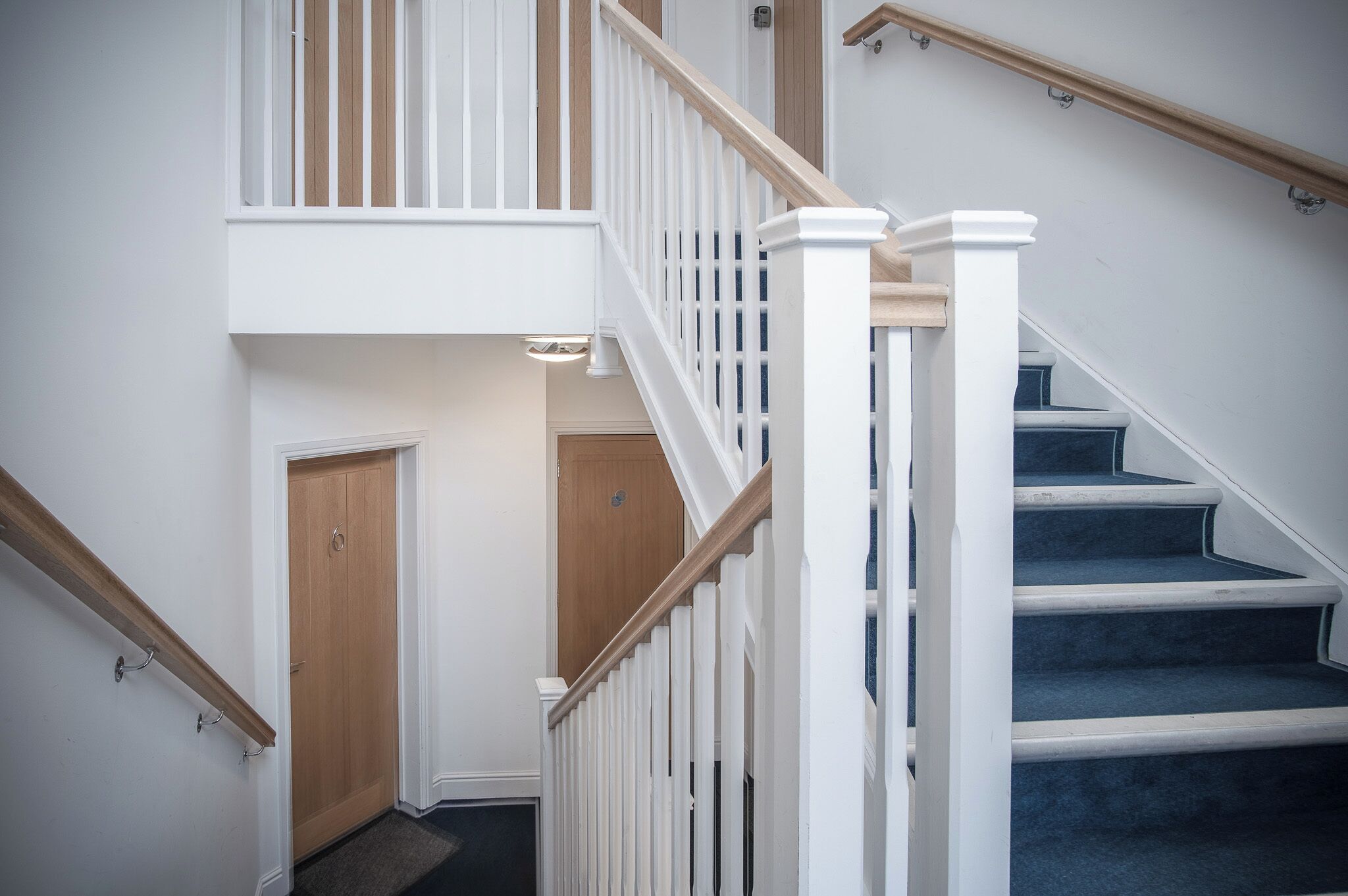 A staircase with white railings and wooden steps, leading to an upper floor.