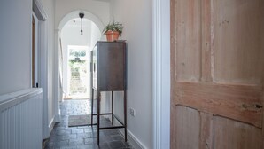 Un couloir avec une porte en bois, une plante en pot et un radiateur.