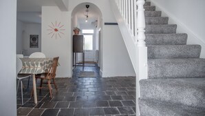 Un escalier avec une rampe blanche et des marches recouvertes d’un tapis gris, menant à un niveau supérieur.