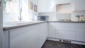 Une cuisine moderne avec des meubles blancs, un four à micro-ondes et une machine à café.