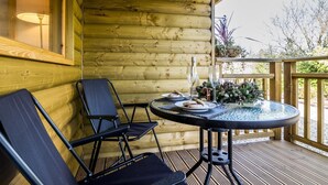 A wooden cabin with a round table and two chairs on a deck.
