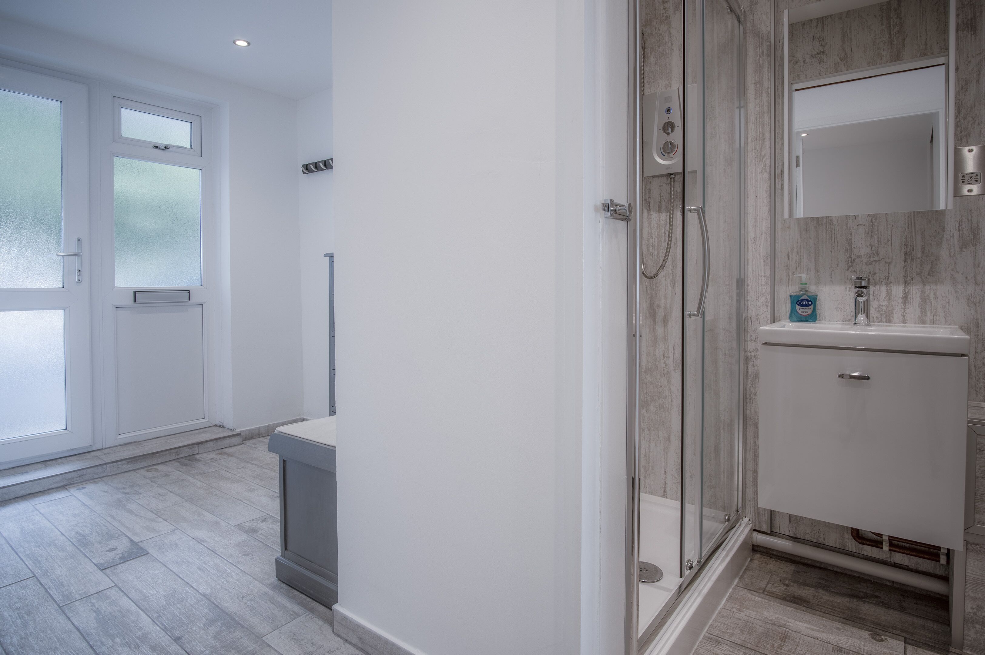 Une salle de bain moderne avec une douche à parois de verre, un lavabo blanc et un miroir au-dessus.