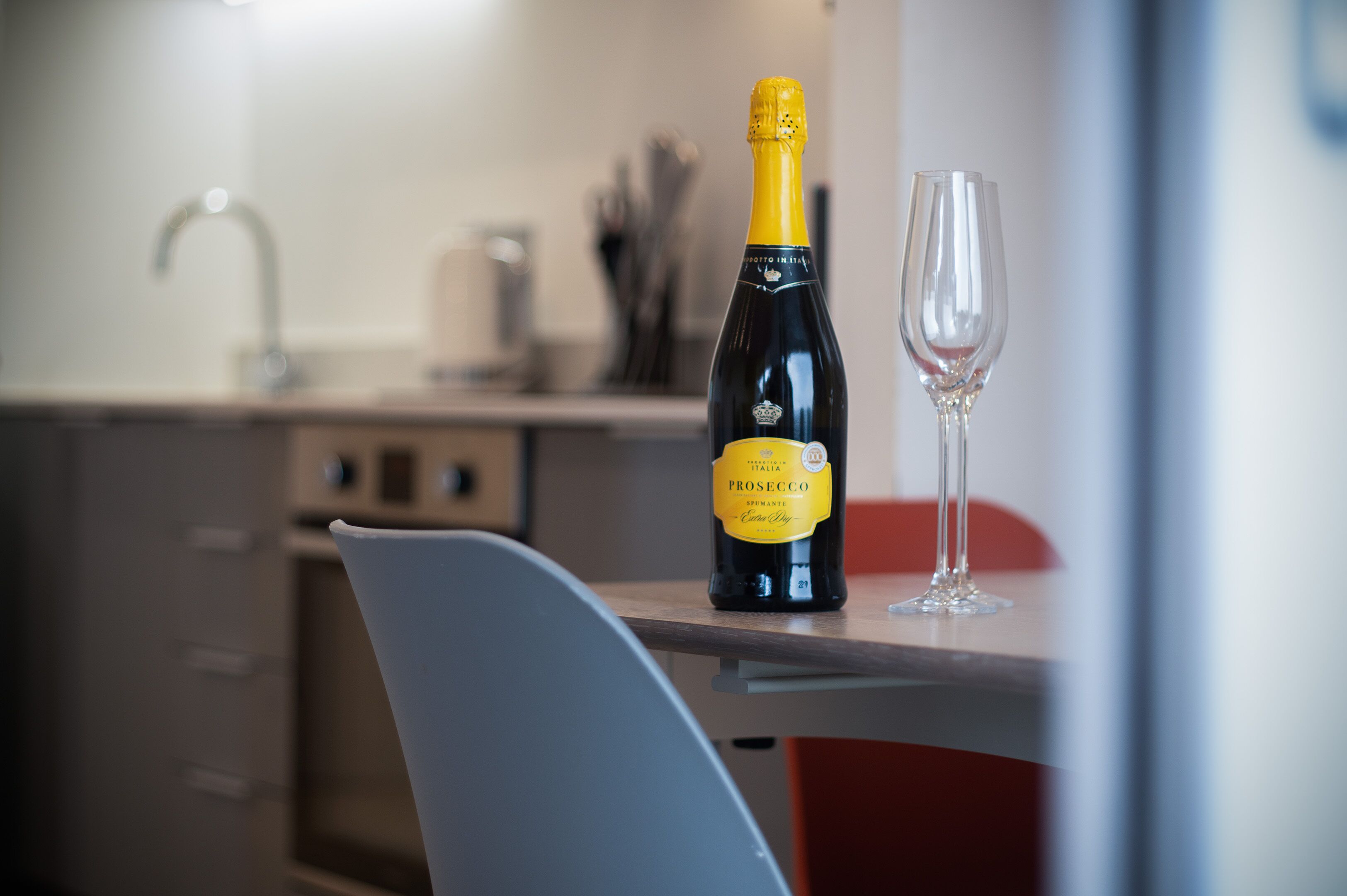 Prosecco-pullo ja viinilasi keittiön työtasolla.