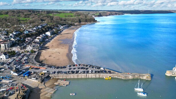 An aerial view of a coastal town with a beach, a harbor, and a mix of residential and commercial buildings. - Beach Court - 1 Bedroom Apartment - Saundersfoot (Saundersfoot)