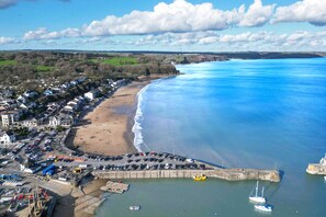 An aerial view of a coastal town with a beach, a harbor, and a mix of residential and commercial buildings. - Beach Court - 1 Bedroom Apartment - Saundersfoot (Saundersfoot)
