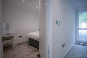 A modern bedroom with a bed, a bedside table, and a window.