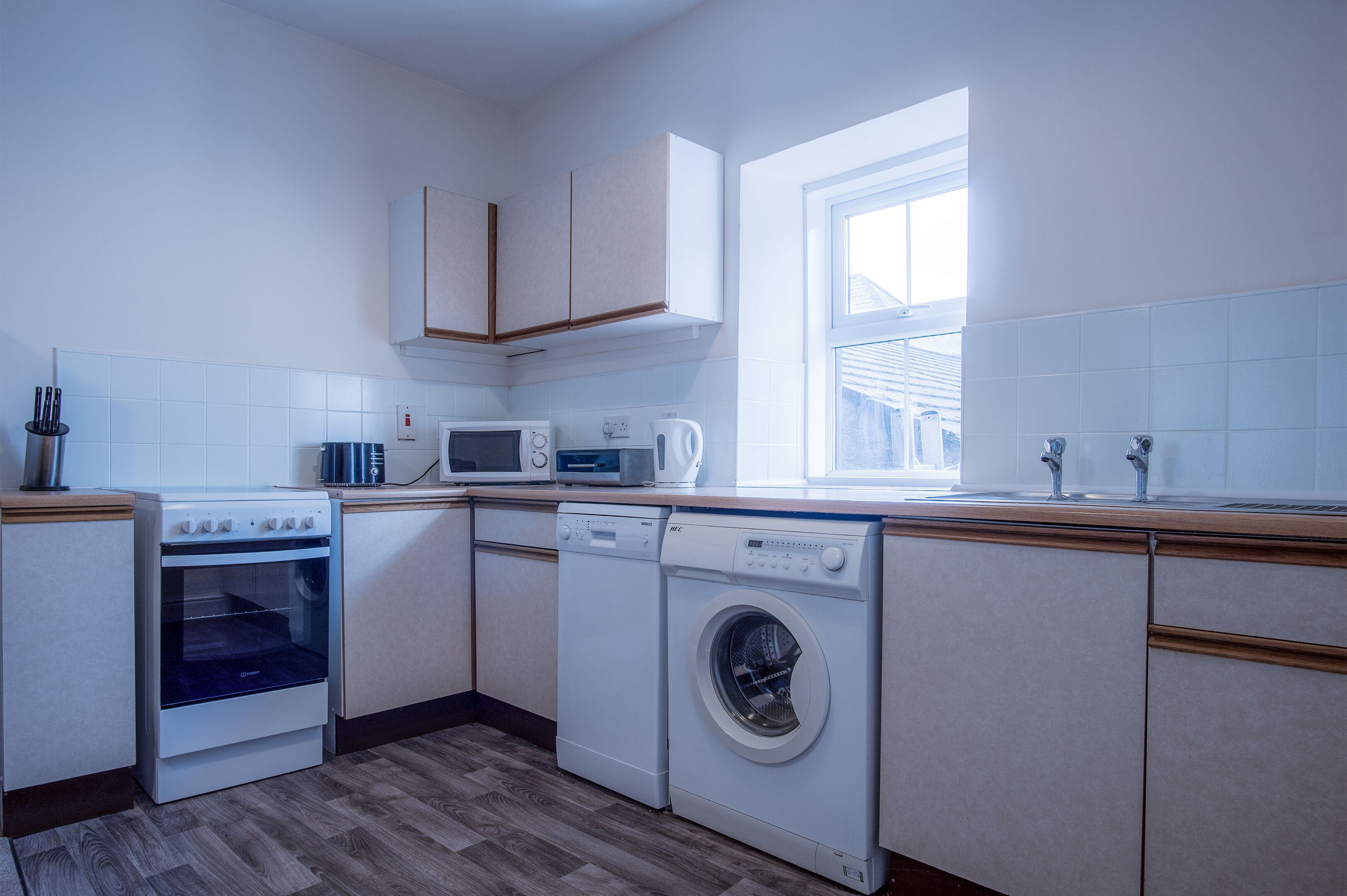 A compact kitchen with a microwave, oven, and washing machine.
