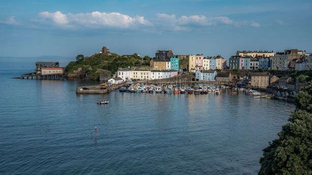A coastal town with colorful buildings, a harbor with boats, and a lighthouse in the distance. - Dragons Den - 2 Bedroom Apartment - Tenby (Tenby)