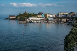 A coastal town with colorful buildings, a harbor with boats, and a lighthouse in the distance.